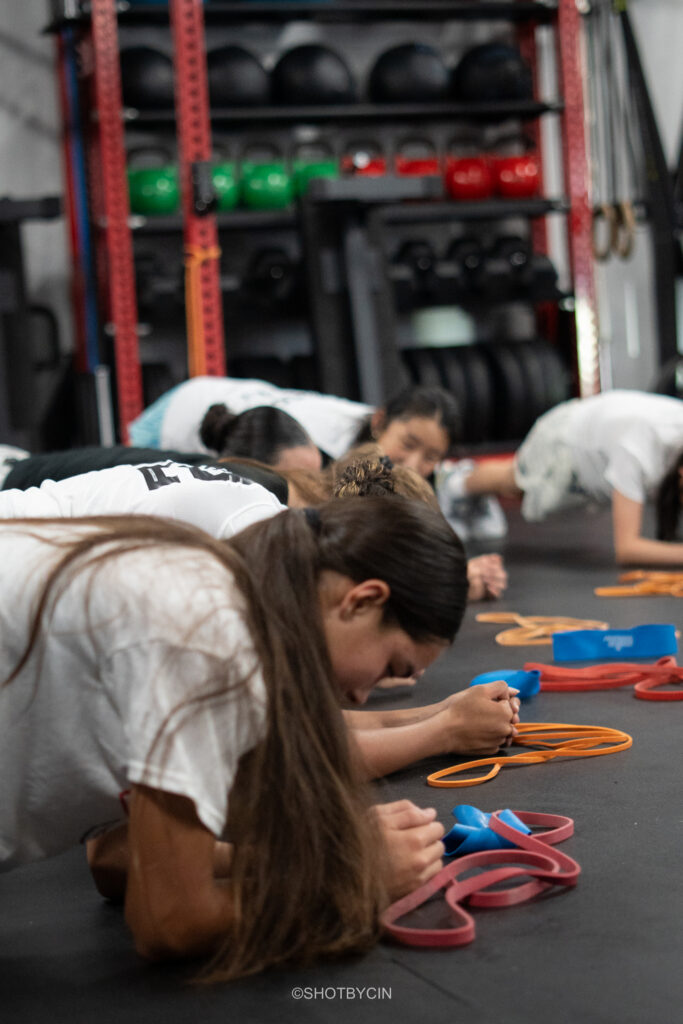 Teen athletes working on the floor with resistance bands during a strength and performance class in Bellevue
